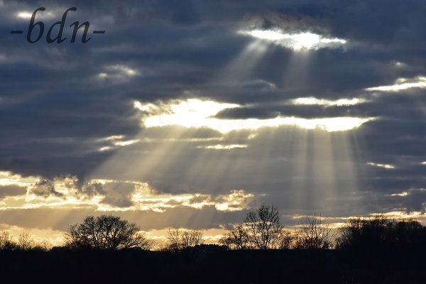 Sonnenstrahlen fallen durch Lücken in der Wolkendecke auf das Ampertal