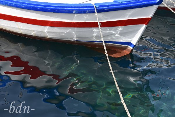 Ein buntes Fischerboot spiegelt sich im Wasser