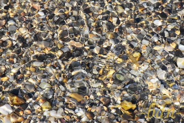 Kieselsteine in einem Bachbett von Wasser überspült