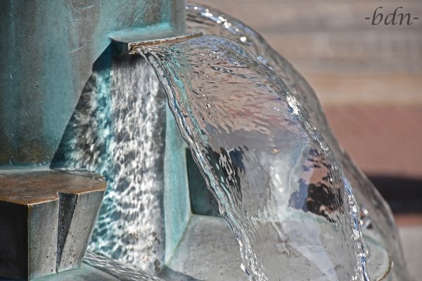 Spiegelungen in fließendem Brunnenwasser