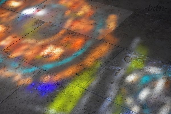 Licht fällt durch ein Kirchenfenster auf graue Natursteinplatten