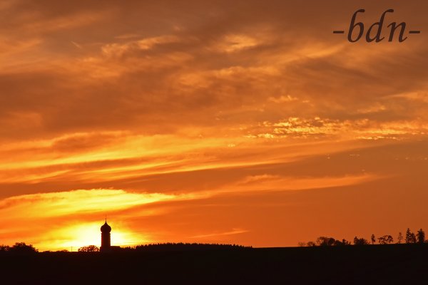 Ein Zwiebelturm am Horizont vor der untergehenden Sonne