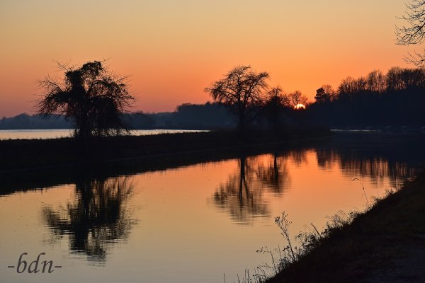 Die Sonne versinkt hinter der Vogelfreistätte Mittlere Isarstauseen